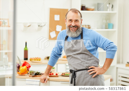Smiling Senior Man Cooking in Kitchen Smiling Senior Man Cooking in Kitchen 58317861