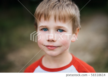 A portrait of school boy standing in nature, looking at camera. A portrait of school boy standing in nature, looking at camera. 58318614