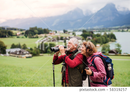 Senior pensioner couple with hiking in nature, using binoculars. Senior pensioner couple with hiking in nature, using binoculars. 58319257