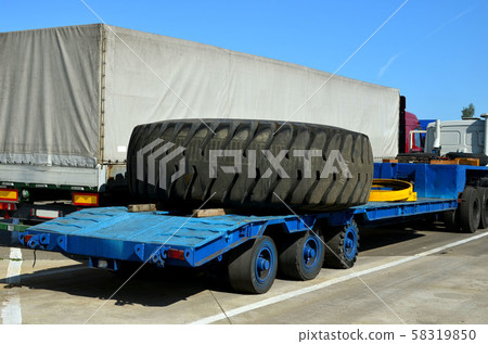 Transporting a large wheel for a mining truck on a truck trailer. Transporting a large wheel for a mining truck on a truck trailer. 58319850