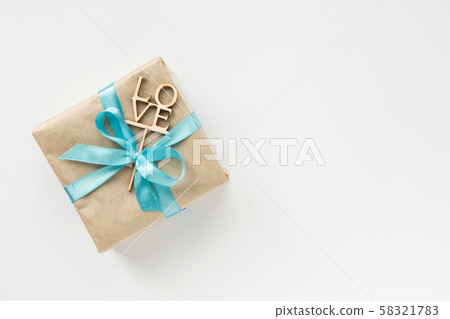 Gift box wrapped in brown paper with blue ribbon 58321783