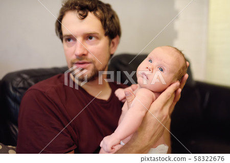Closeup portrait of cute newborn baby lying in arms of his father. 58322676