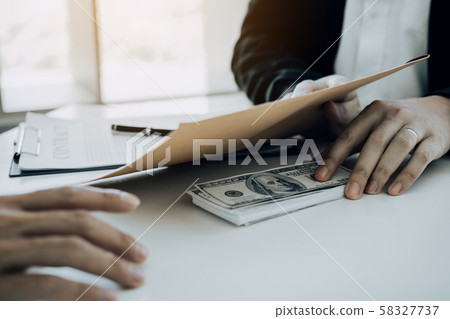 Businessman secretly giving a bribe by giving 58327737