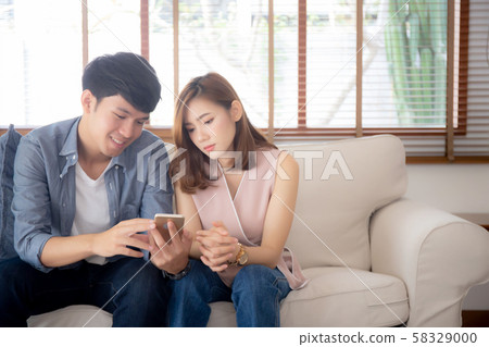 Young asian couple or friend looking smart mobile phone with enjoy at living room 58329000