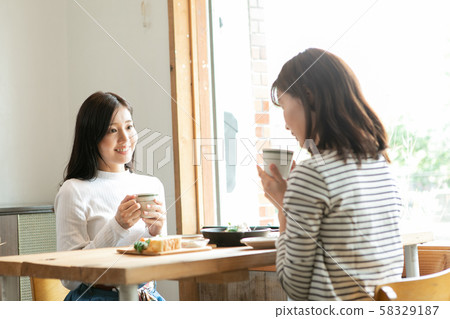 Female duo relaxing in a bright cafe Female duo relaxing in a bright cafe 58329187