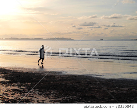 Silhouette of a man running in the beach during 58330848
