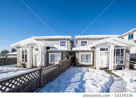 Residential duplex house with front yard in snow on bright winter day in Canada Residential duplex house with front yard in snow on bright winter day in Canada 58334336