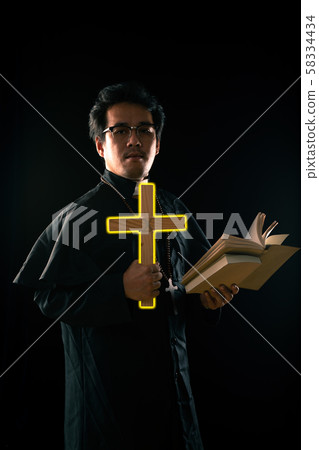 Priest show lighting crucifix while holding bible to exorcise ghost 58334434