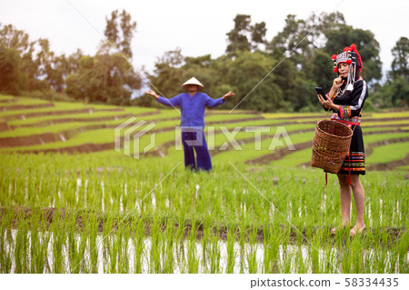 Female Asian Hmong holding mobile phone and wonder feeling while male farmer stop working 58334435
