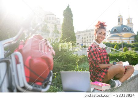 Student studying outside using laptop and books 58338924