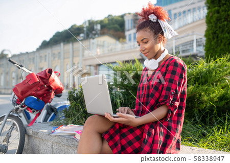 Red-haired student enjoying online lesson while sitting outside Red-haired student enjoying online lesson while sitting outside 58338947