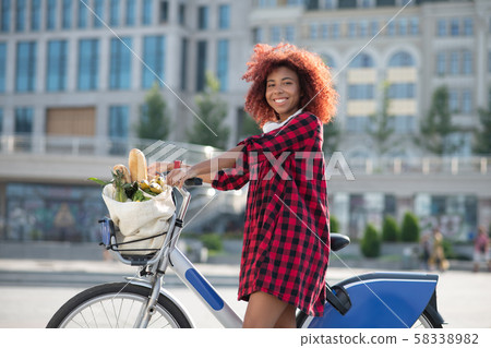 Cheerful curly woman feeling happy after buying foods 58338982