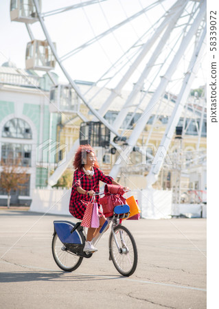 Curly woman riding bike on the way home after shopping 58339072