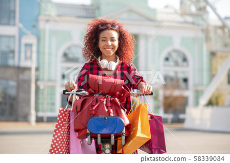 Smiling woman caring many shopping bags after shopping 58339084