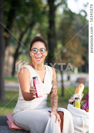 Woman with tattooed arm holding bottle with smoothie 58345879