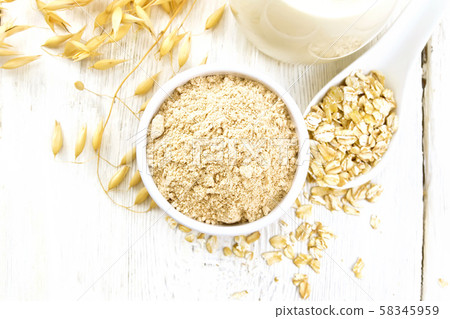 Flour oat in bowl with milk on light board top Flour oat in bowl with milk on light board top 58345959