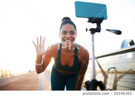 Woman waving to her followers while making sports blog 58346365