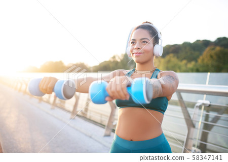 Dark-eyed woman taking dumbbells and building muscles 58347141