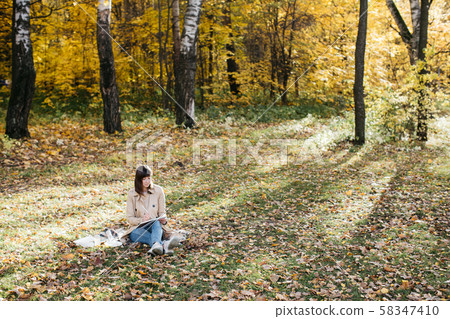 A young girl sketching near a lake in the autumn forest. Sketching 58347410