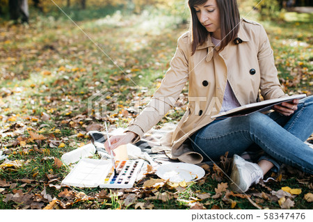 A young girl sketching near a lake in the autumn forest. Sketching 58347476