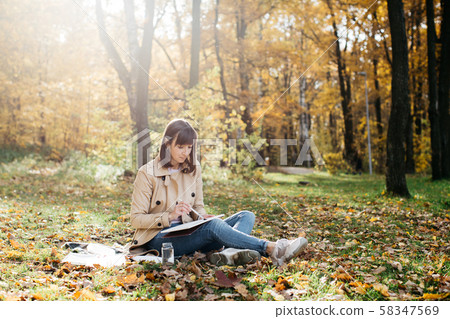 A young girl sketching near a lake in the autumn forest. Sketching 58347569