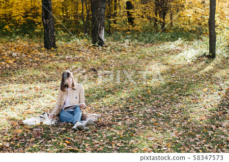 A young girl sketching near a lake in the autumn forest. Sketching 58347573