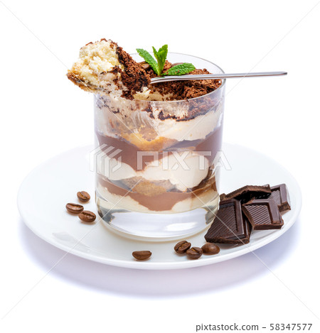 Classic tiramisu dessert in a glass cup on the plate and pieces of chocolate on white background 58347577
