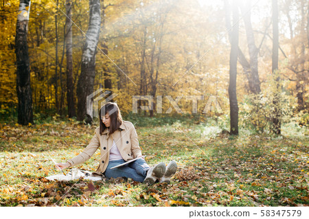 A young girl sketching near a lake in the autumn forest. Sketching 58347579