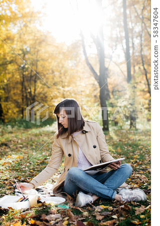 A young girl sketching near a lake in the autumn forest. Sketching A young girl sketching near a lake in the autumn forest. Sketching 58347604