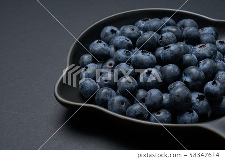 Blueberries on a black clay pan with black background, closeup view. 58347614