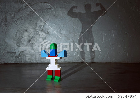 Plastic building blocks with muscle man shadow . Creative and ideal concept . Concrete interior background . Plastic building blocks with muscle man shadow . Creative and ideal concept . Concrete interior background . 58347954