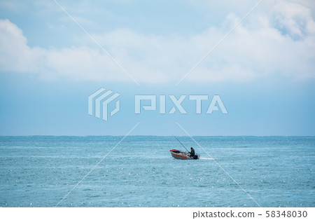 A fisherman is sailing in a boat. A fisherman is sailing in a boat. 58348030