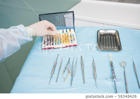 The dentists hand takes the endodontic obstructive 58348426