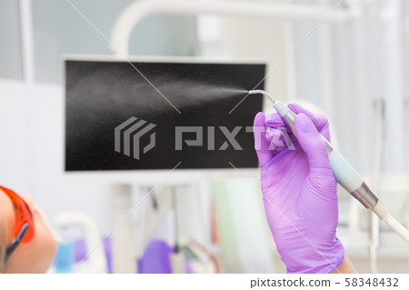 Close-up teeth airflow tool in the hand. 58348432