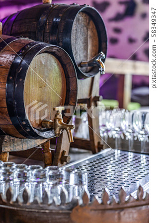 Old oak barrel with whiskey spirit small glases on a wooden table. in front of blurred background 58349347