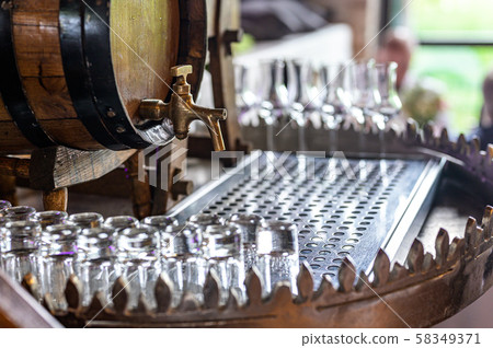 Old oak barrel with whiskey spirit small glases on a wooden table. in front of blurred background 58349371