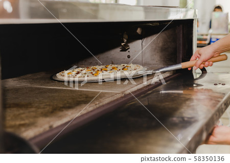 Chef putting pizza in the oven with pizza shovel equipment. Chef putting pizza in the oven with pizza shovel equipment. 58350136