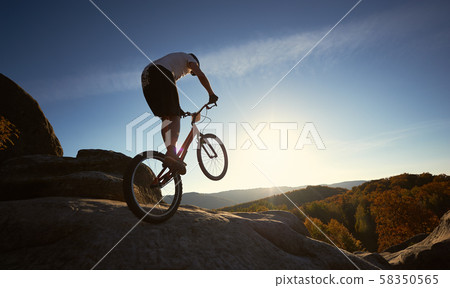 Sportsman cyclist balancing on back wheel on trial bicycle Sportsman cyclist balancing on back wheel on trial bicycle 58350565