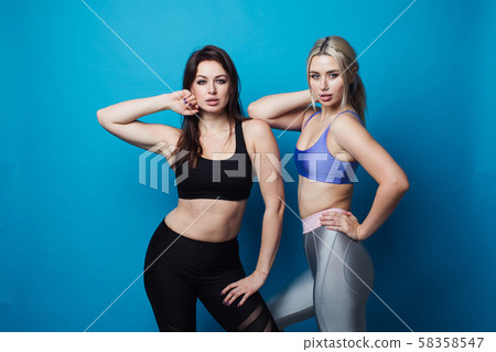 Two happy and cheerful girls dressed in fitness bodysuits, best friends having fun. 58358547