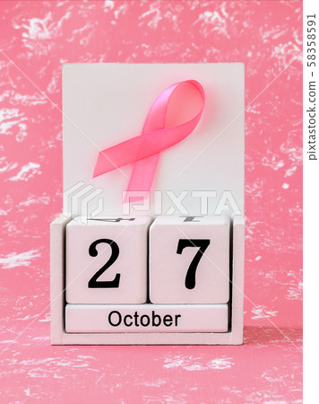 Pink ribbon of breast cancer awareness on a white wooden perpetual calendar with date 27 october. Pink ribbon of breast cancer awareness on a white wooden perpetual calendar with date 27 october. 58358591