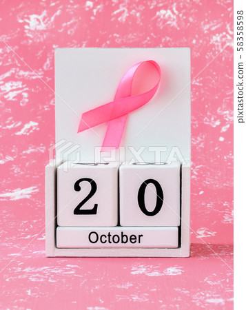 Pink ribbon of breast cancer awareness on a white wooden perpetual calendar with date 20 october. Pink ribbon of breast cancer awareness on a white wooden perpetual calendar with date 20 october. 58358598