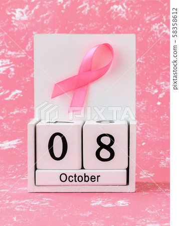Pink ribbon of breast cancer awareness on a white wooden perpetual calendar with date 08 october.  58358612