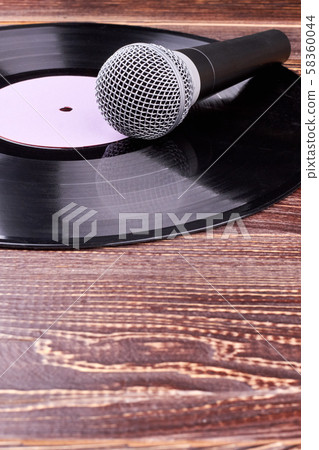 Grey microphone and vinyl record on wooden background. Grey microphone and vinyl record on wooden background. 58360044