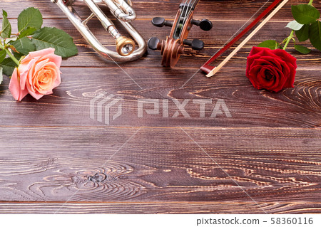 Musical instruments and roses on wooden background. 58360116