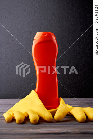 Detergent bottle and gloves on dark background. 58361124