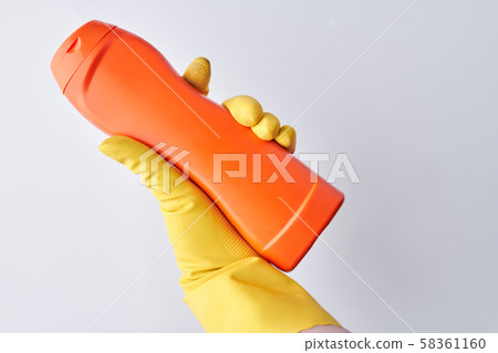 Hand holding detergent on light background. 58361160