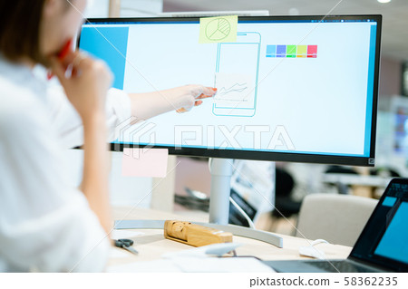 A woman in her twenties working at a monitor A woman in her twenties working at a monitor 58362235