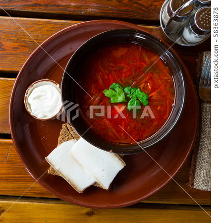 Ukrainian borscht red-beet soup on bowl, served with bread and salo Ukrainian borscht red-beet soup on bowl, served with bread and salo 58363878