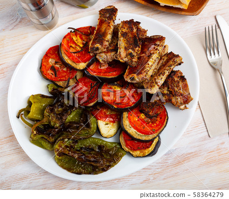 Grilled pork ribs rack garnished on white plate with eggplant; tomatoes and bell pepper Grilled pork ribs rack garnished on white plate with eggplant; tomatoes and bell pepper 58364279