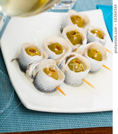Appetizing herring rolls with olives on skewers 58364384